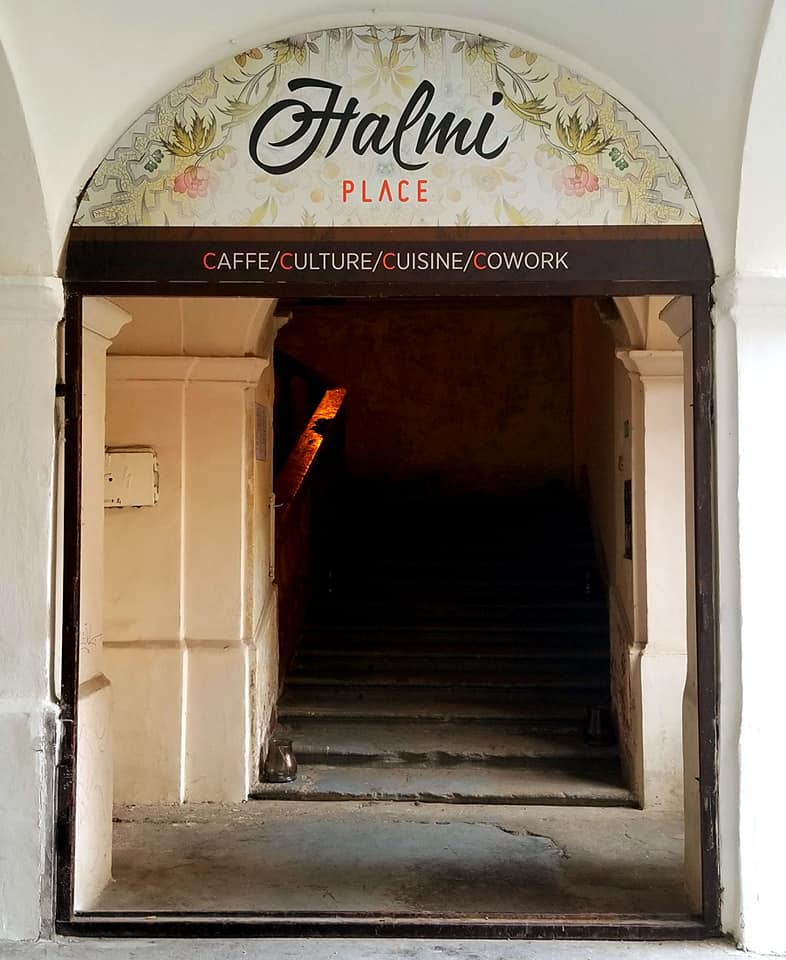 Entrance to Halmi Place, a coffee shop/co-op in Kosice, Slovakia. There are two double doors that offer a wide entrance. On top of the doors it says 'Halmi Place' written in cursive.