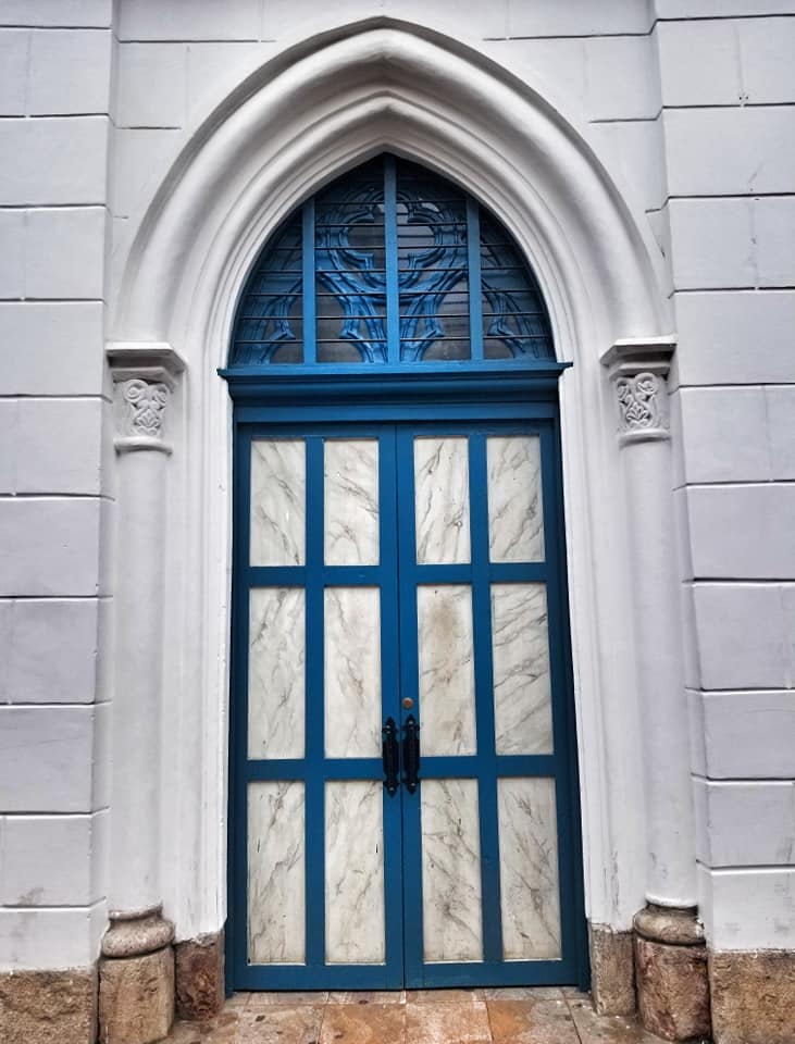 Teal door in Cuenca, Ecuador on white building.