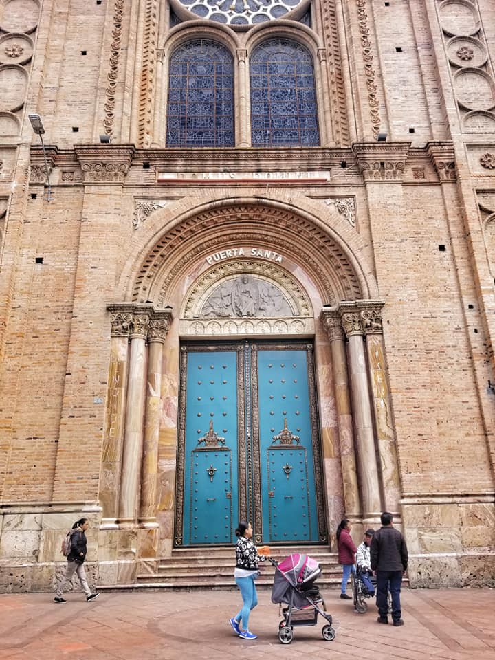 Turquoise door in Cuenca, Ecuador on sand colored building.