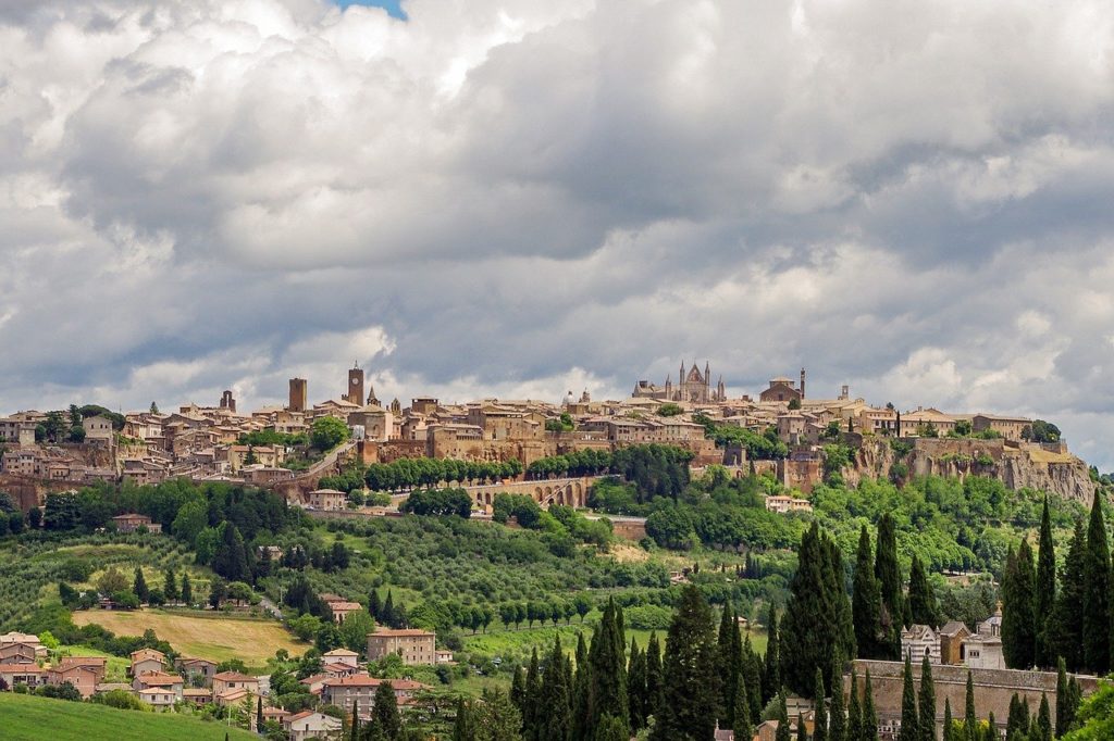 View of the Umbrian town, Orvieto, set atop a tufo rock with rolling green hills in the foreground.